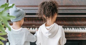Photo of two children playing piano together